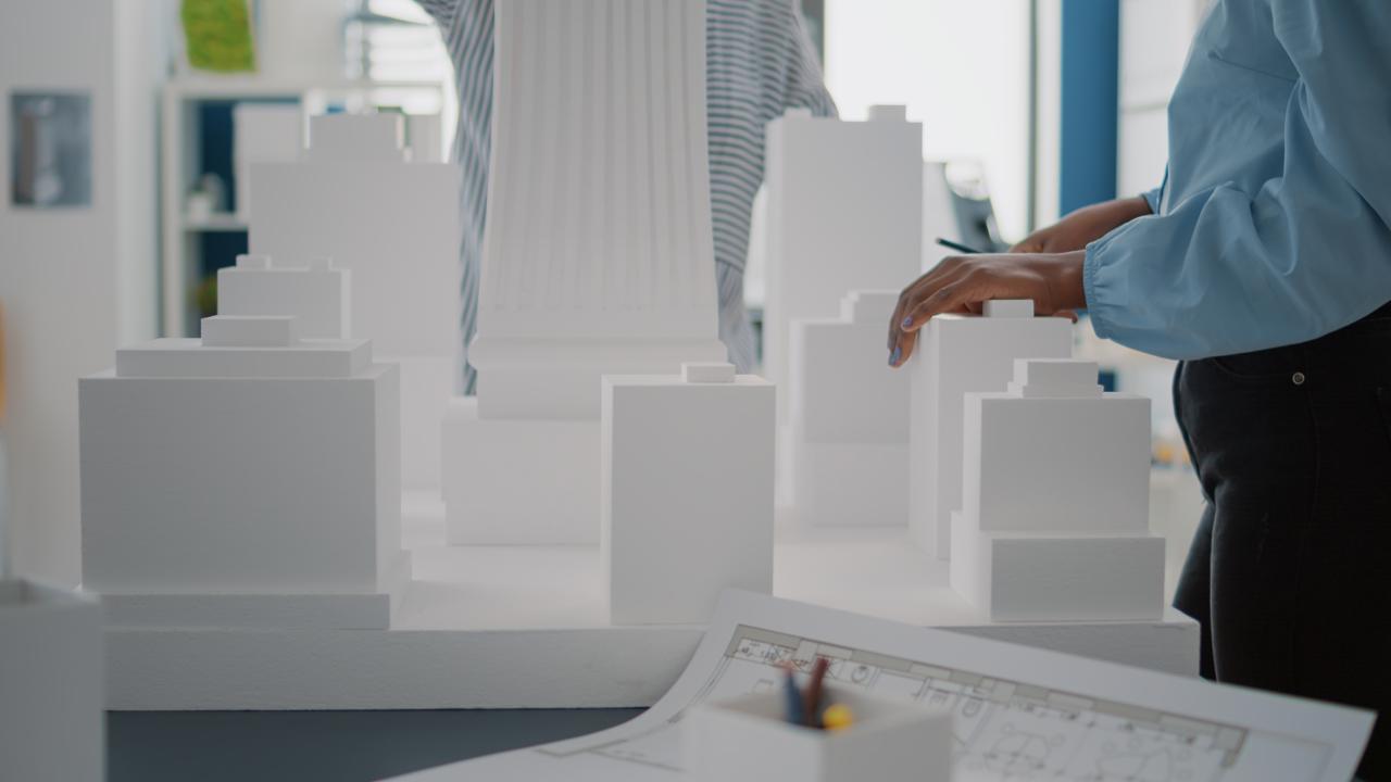close-up-women-with-building-model-blueprints-plan-table-diverse-architects-working-with-maquette-industrial-sketch-design-construction-structure-strategy-project