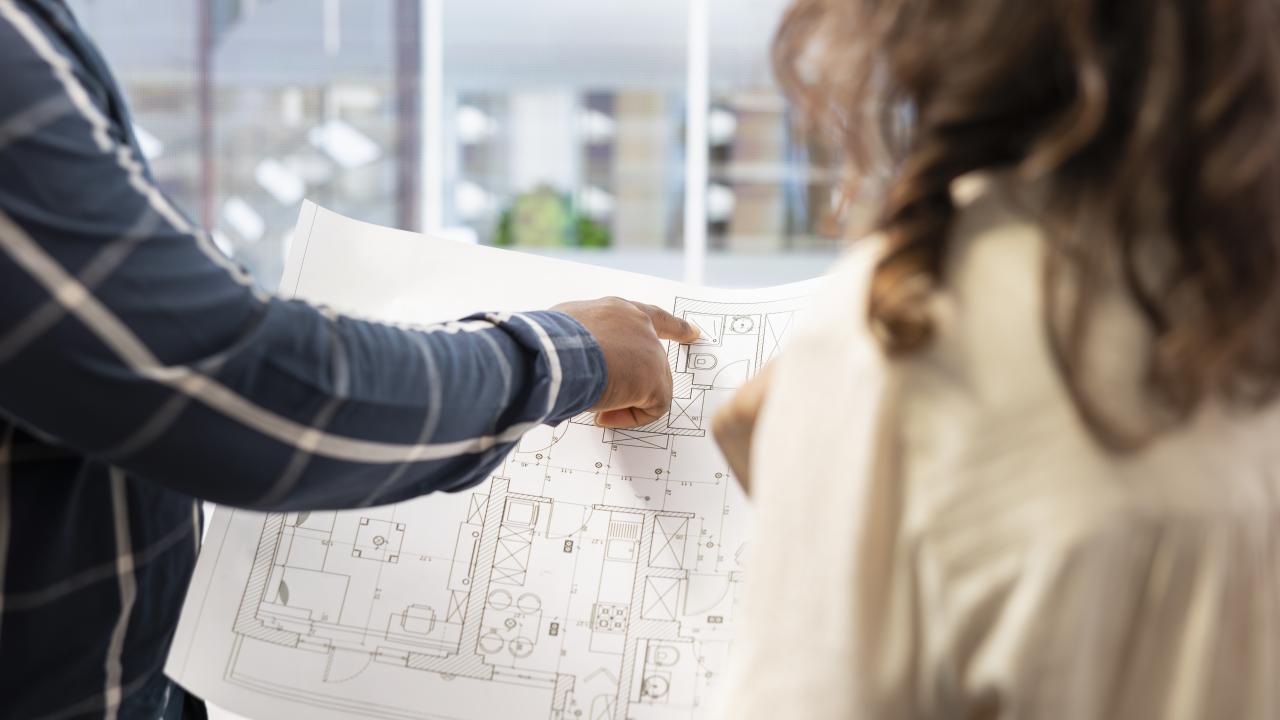 real-estate-expert-presenting-office-space-layout-woman-using-blueprints