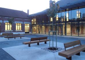 Photographie nocturne de la galerie de distribution vitrée depuis la cour de réc