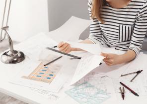 close-up-detail-female-engineer-wearing-striped-clothes-sitting-white-big-table-looking-through-papers-working-construction-project